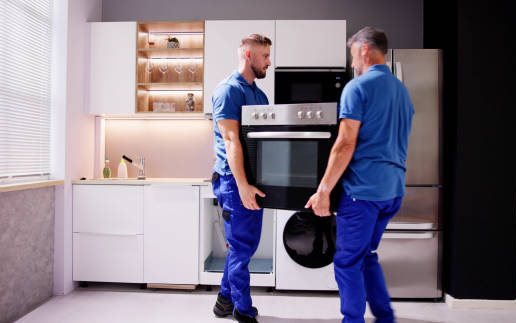 Cooker being moved into place in a kitchen