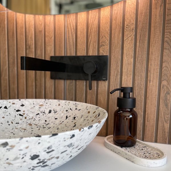 Terrazzo basin with wall-mounted black tap and fluted panelling