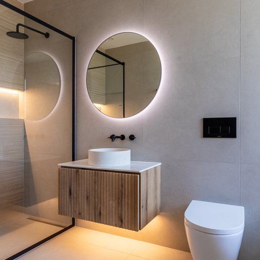 Fluted oak vanity with round backlit mirror and walk-in shower
