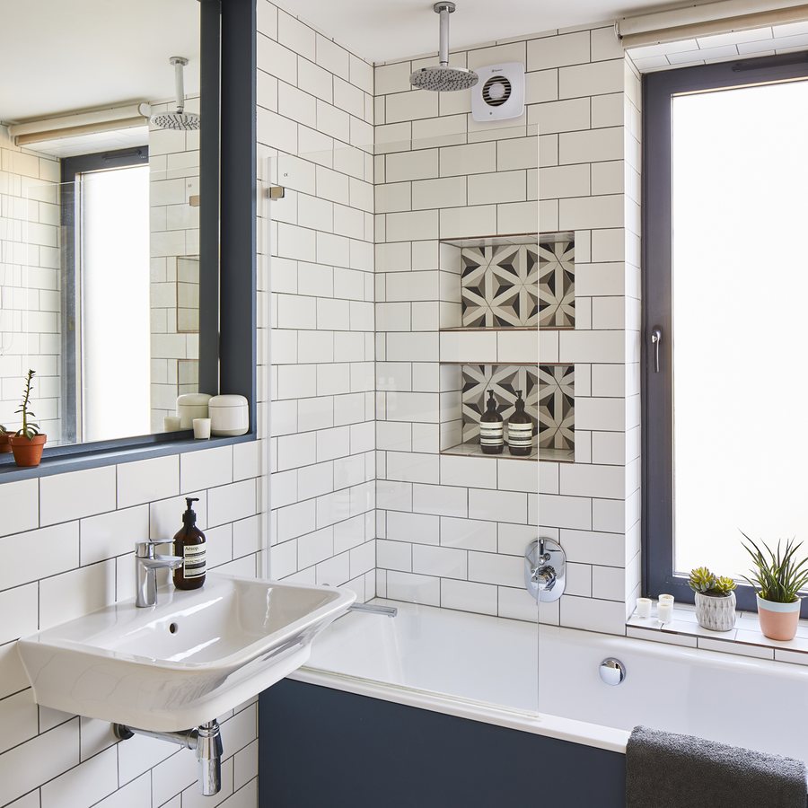 Metro tiled bathroom with navy bath panel and geometric floor tiles