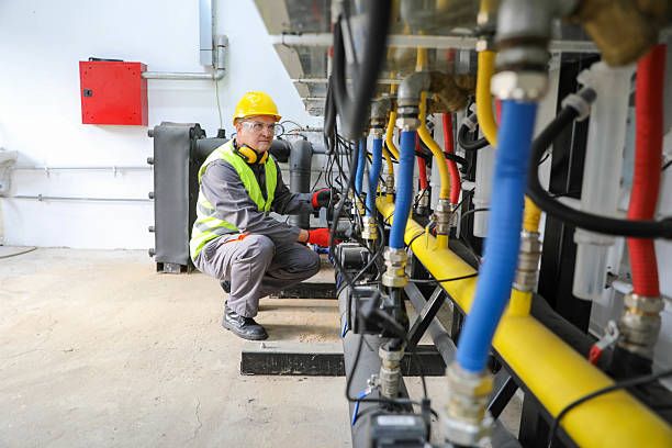 Engineer in hi-vis checking pipework manifolds in a plant room