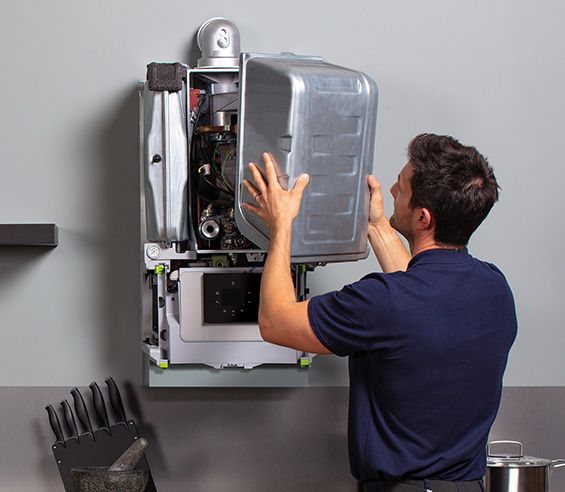 Engineer lifting the front casing off a wall-hung boiler