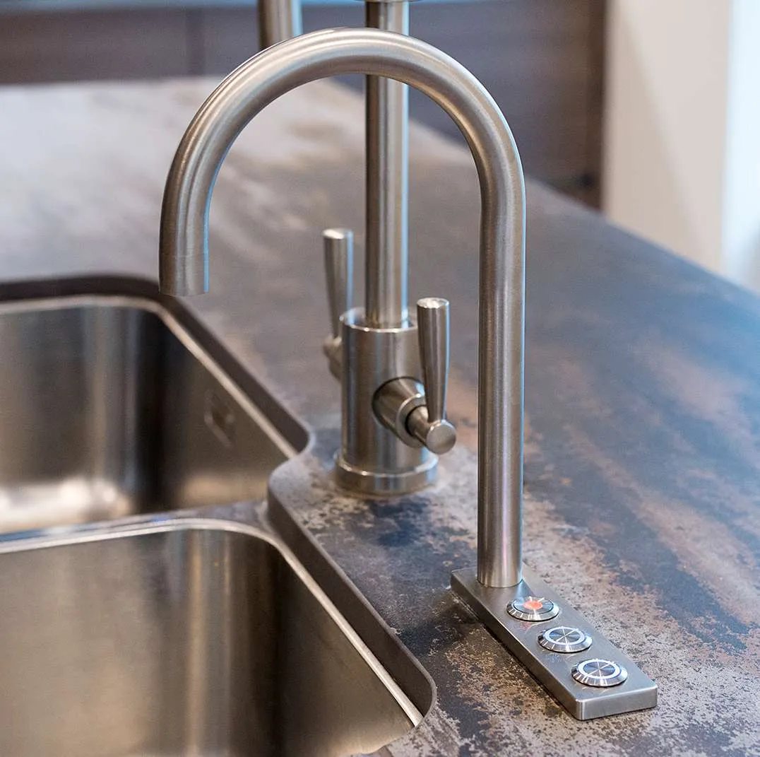 Brushed steel boiling water tap with control buttons beside an undermounted sink