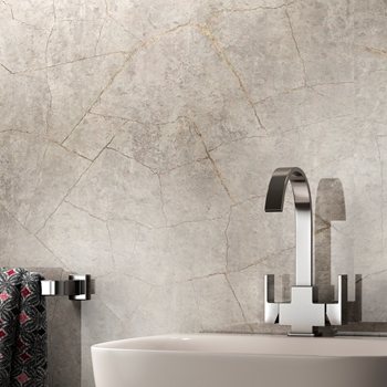 Chrome mixer tap on a basin against a stone-effect wall panel
