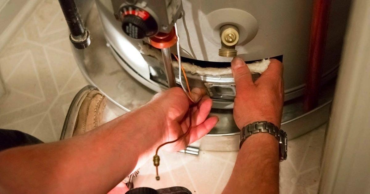Engineer replacing the thermocouple on a gas-fired storage water heater