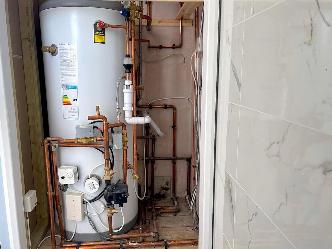 Unvented cylinder cupboard with motorised valves, pump and neatly run copper pipework