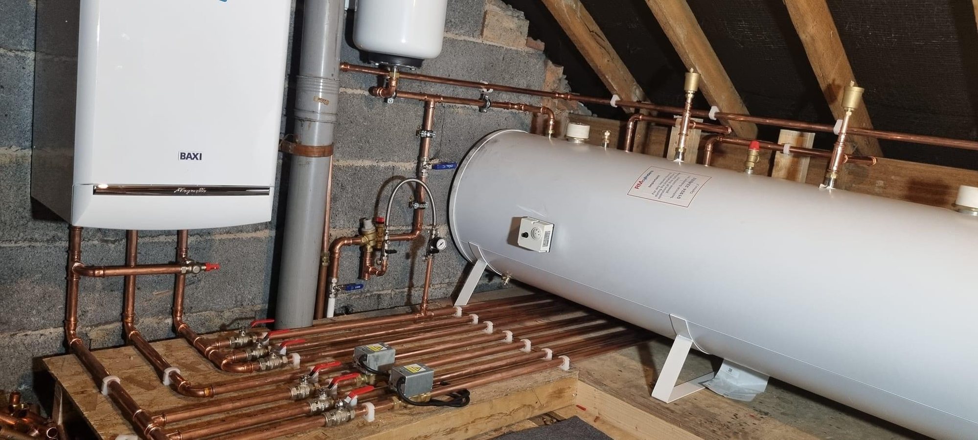 Loft installation: Baxi system boiler and a horizontal unvented cylinder, with the primaries run across a purpose-built platform.