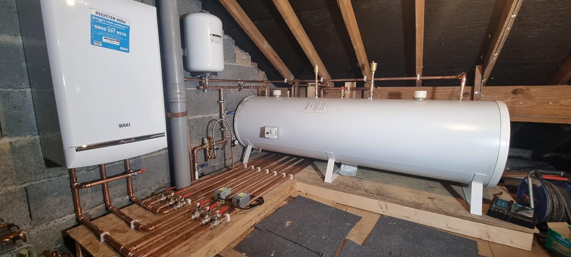 The same loft job from the other side, showing the zone valves, isolation and the boarding laid before any pipework went in.
